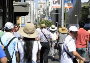 En la imagen turistas y madrilenos usan sombreros y gorras paseando por Gran Via