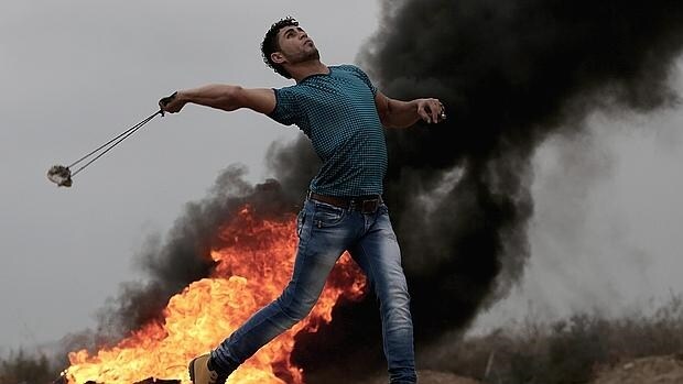 Un palestino tira piedras a los soldados israelíes en la frontera con la Franja de Gaza