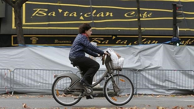 Una mujer pasa con su bicicleta frente a la discoteca Bataclan