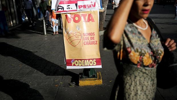 Una mujer en Caracas junto a propaganda chavista