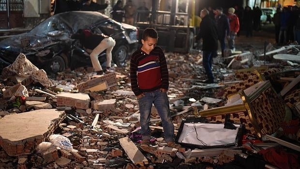 Un niño mira los destrozos que ha dejado el coche bomba en una calle de Giza