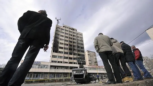 Civiles bosnios observan los desperfectos causados por unos manifestantes en una imagen de archivo