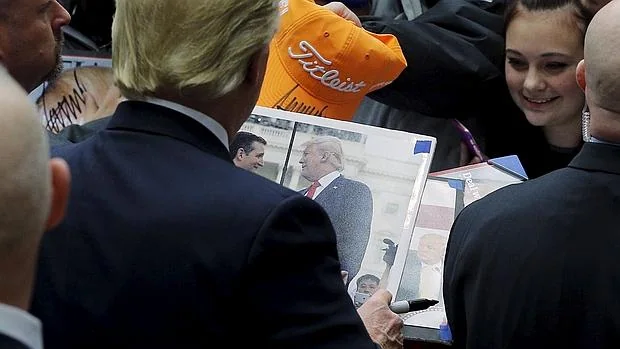 Donald Trump firma un autógrafo sobre una foto de él mismoy de Cruz