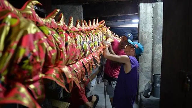 Trabajadores arreglan un vestido de dragón gigante antes del Año Nuevo Chino