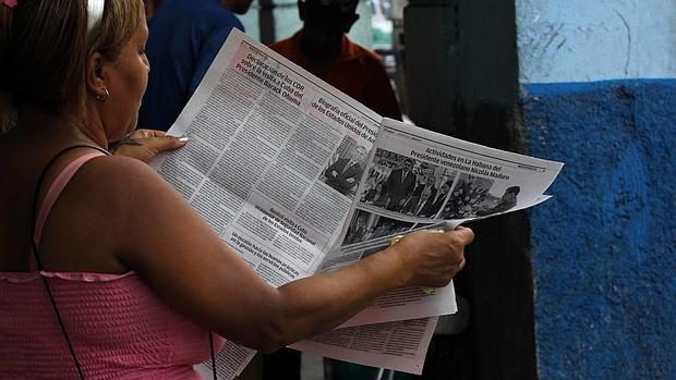 Una mujer lee el diario oficial Granma con la noticia de la visita del presidente de los Estados Unidos a Cuba