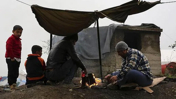 Una familia de refugiados trata de calentarse junto a una hoguera en el campamento provisional de Idomeni