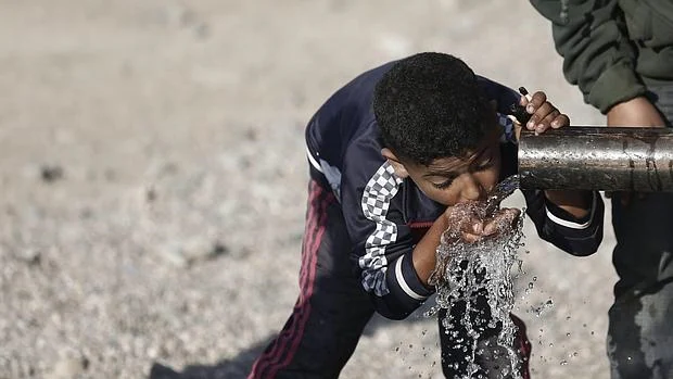 Un niño sirio refugiado en Idomeni bebe agua