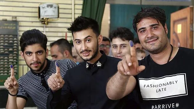 Varios hombres muestran sus dedos tintados después de haber votado en Irán