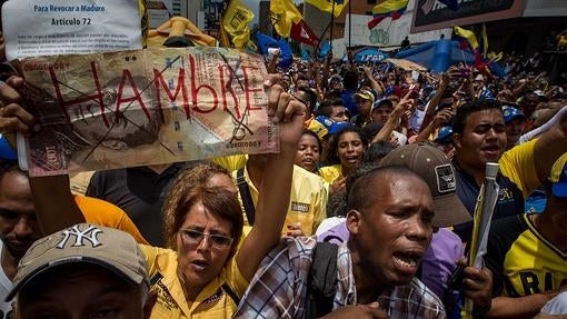 Una manifestante sostiene un letrero con la palabra «Hambre», durante una protesta para reclamar un referéndum revocatorio contra Nicolás Maduro, el pasado sábado en Caracas