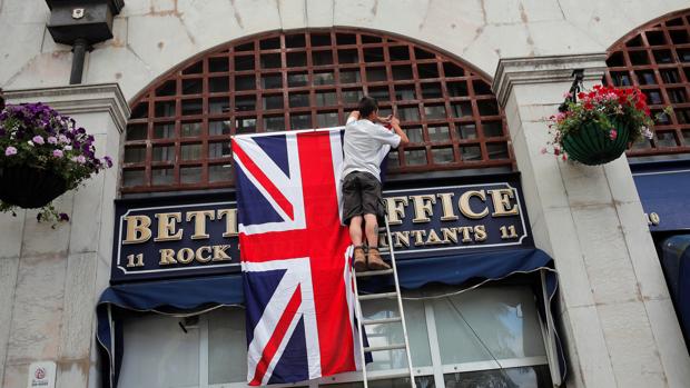 Un trabajador coloca la bandera de la Uniion Jack en una tienda de la plaza Casemates