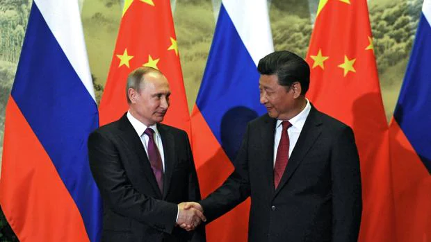 El presidente chino, Xi Jinping, da la mano a su homólogo ruso Vladimir Putin, en la ceremonia de bienvenida a Beijing