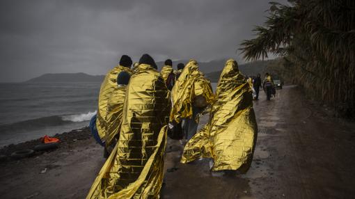 Un grupo de refugiados abandona la playa de la isla de Lesbos a la que llegaron en patera