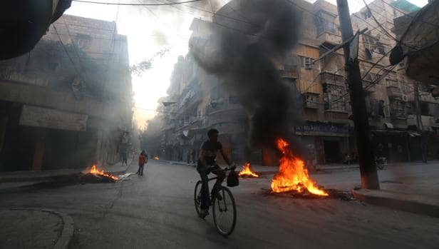 Un hombre en bici pasa al lado de una hoguera creada para prevenir los bombardeos