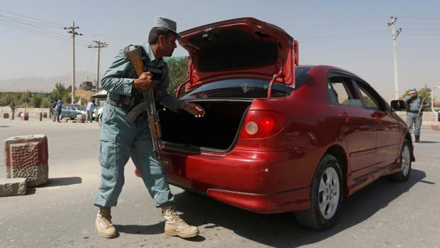 Un policía afgano registra un coche hoy cerca del lugar donde ha sido el secuestro