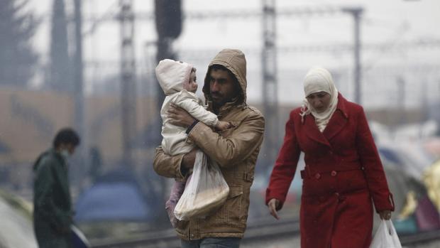 Una familia de refugiados espera cerca de Idomeni (Grecia) para cruzar la frontera con Macedonia