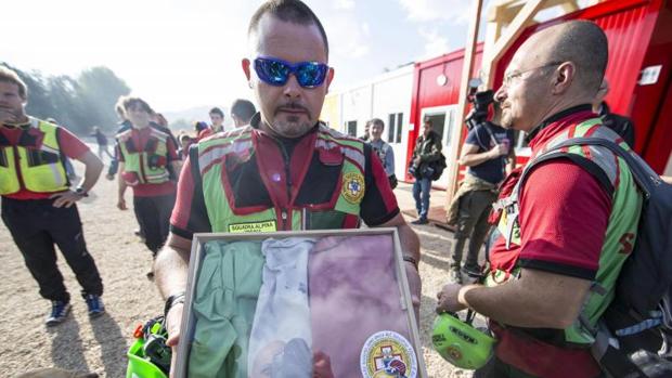 Un voluntario sujeta la antigua bandera de Amatrice recuperada por los servicios de rescate delante de un improvisado colegio en Amatrice