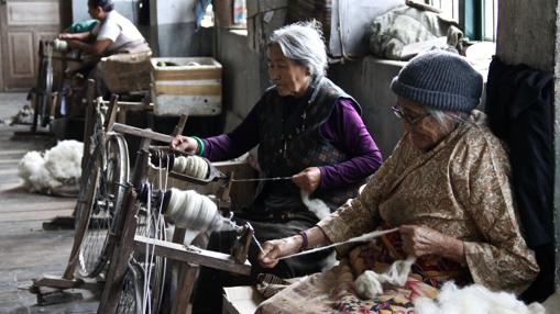 Dolma y Sangmo, dos ancianas que huyeron del régimen chino en 1959, tejen lana en un taller del Centro de Autoayuda para Refugiados Tibetanos de Darjeeling.