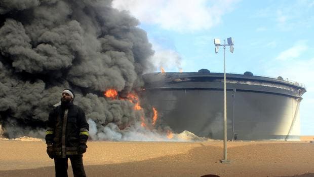 Un bombero junto a tanque de almacenaje de petróleo en llamas en Ras Lanuf
