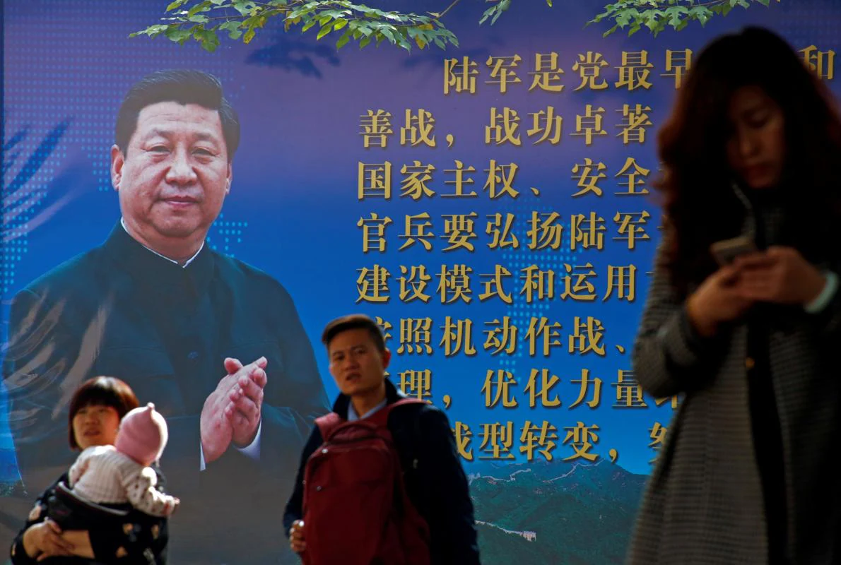 La gente camina delante de un póster del presidente chino, Xi Jinping