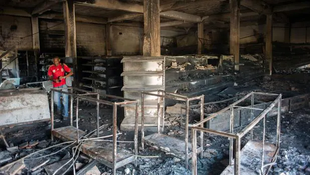 Un hombre inspecciona un almacén quemado por los saqueadores en Ciudad Bolívar, en estado Bolívar