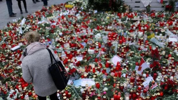 Una mujer observa las flores y las velas puestas en la plaza Breitscheid en honor a las 12 víctimas del ataque del pasado 19 de diciembre contra el mercadillo de Navidad
