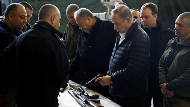 Benjamin Netanyahu sostiene una pistola que el Ejército israelí asegura que confiscó en Cisjordania, durante una visita el martes a la base militar del asentamiento de Beit El near, cerca de Ramala