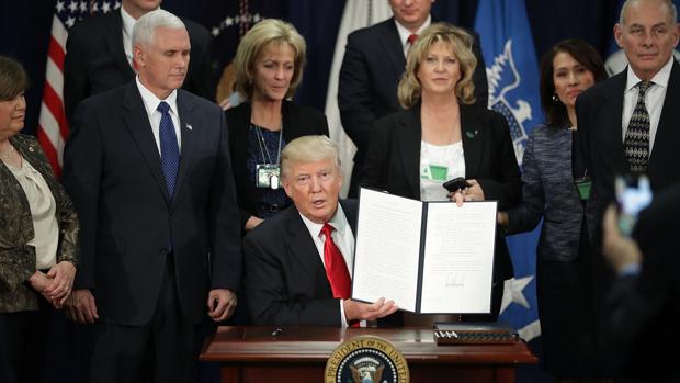 El presidente estadounidense, Donald J. Trump (c), enseña la firma de la orden ejecutiva para destinar fondos federales a la construcción del muro con México durante una ceremonia en el Departamento de Seguridad Nacional en Washington