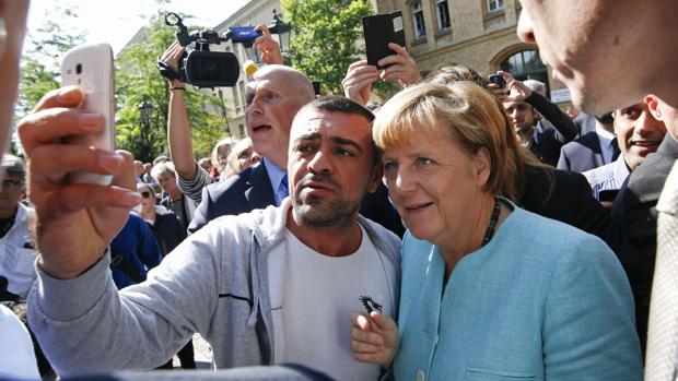 Un refugiado se fotografía con Merkel en un centro de acogida de Spandau