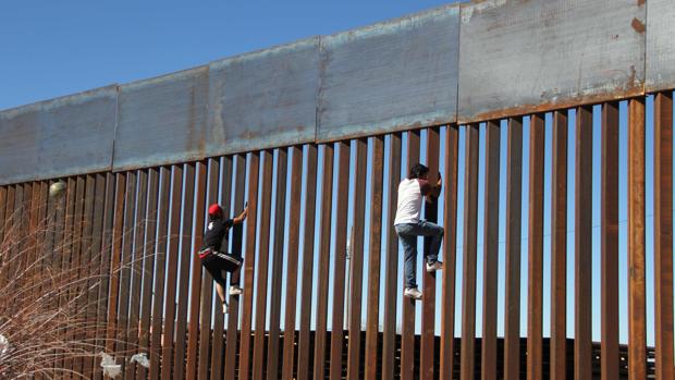 Dos hombres escalan el muro que separa Estados Unidos de México en Ciudad Juárez