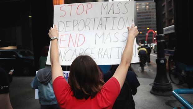 Una manifestante marcha por la calles de Chicago con una pancarta en la que pide por el fin de las deportaciones masivas