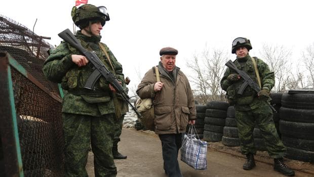 Rebeldes prorrusos custodian el control de Stanytsia Luhanska, en la región de Lugansk, mientras un hombre se dirige al territorio bajo control de Ucrania, la semana pasada