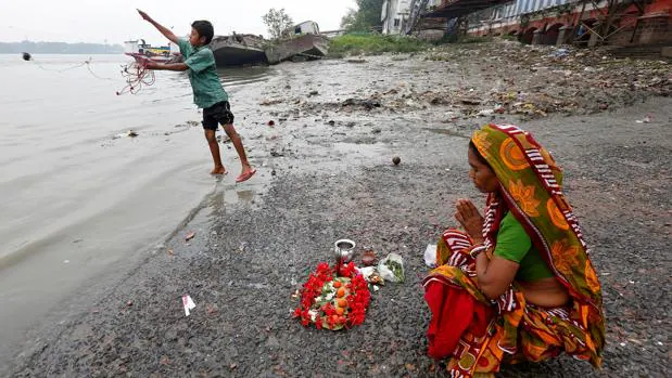 Una mujer reza a la orilla del Ganges