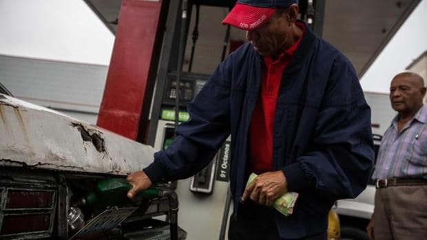 Un venezolano llena el depósito de combustible en una gasolinera de Caracas