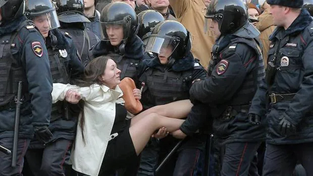 Un grupo de policías antidisturbios rusos detienen a una mujer durante la manifestación de ayer en Moscú