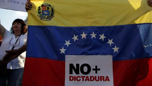 Un joven porta una bandera en una protesta en Caracas en la que se lee «No más dictadura»