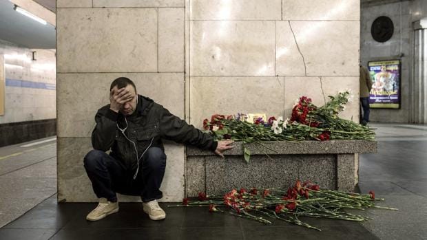 Un hombre llora junto a un banco lleno de flores en un andén de la estación de metro Tejnologuícheskiy Institut, en memoria de las víctimas del atentado de San Petersburgo