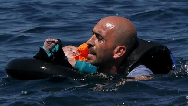 Un refugiado sirio y su bebé, a punto de llegar a la isla griega de Lesbos