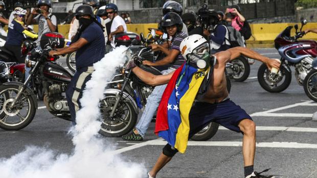 Un manifestante opositor se enfrenta a integrantes de la Guardia Nacional Bolivariana (GNB)