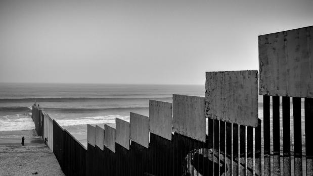 Dos personas pasean junto al muro fronterizo que separa México y Estados Unidos en Tijuana