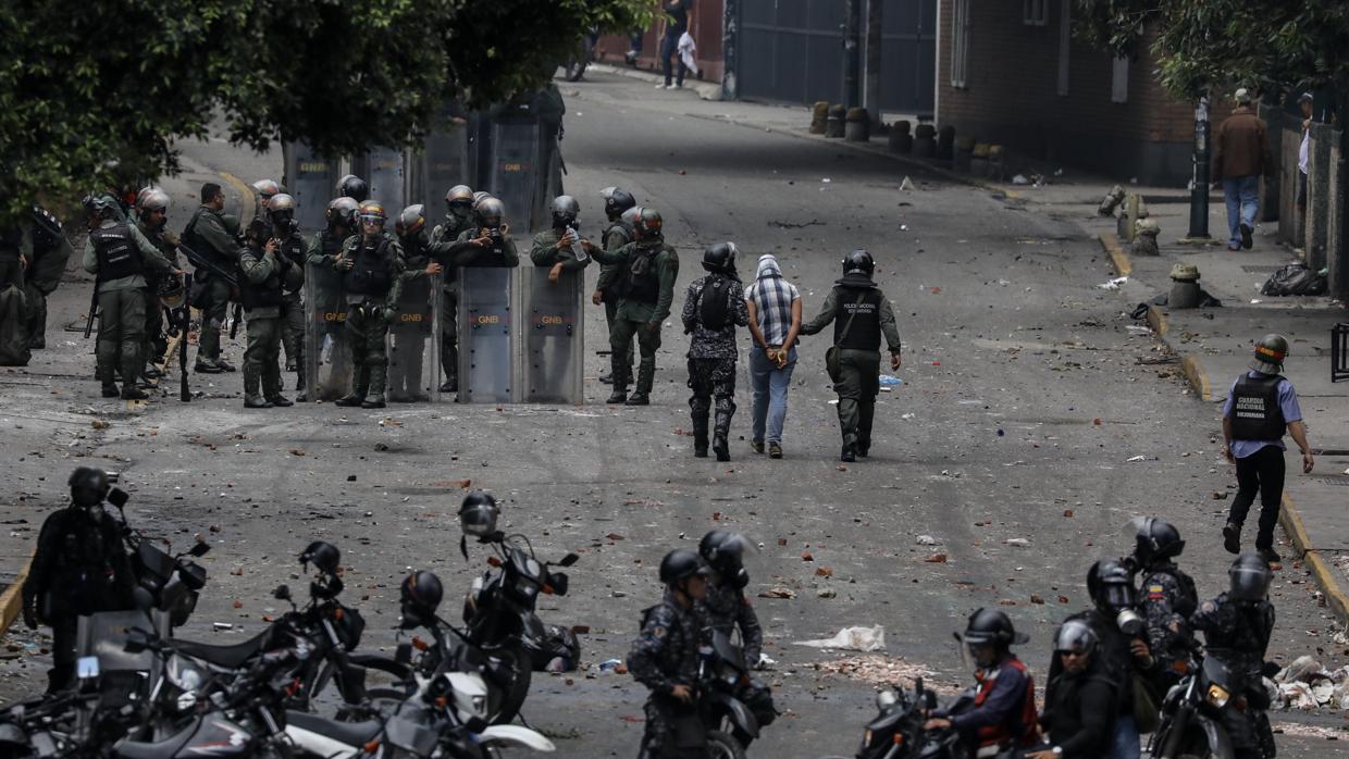 Miembros de la Guardia Nacional Bolivariana (GNB) detienen a un manifestante opositor