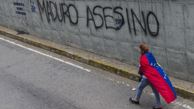 Una mujer camina frente a un grafiti durante una manifestación antigubernamental