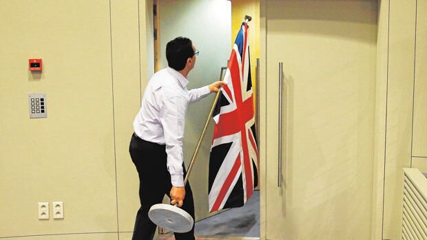 Un funcionario lleva una bandera del Reino Unido, en la sede de la CE en Bruselas