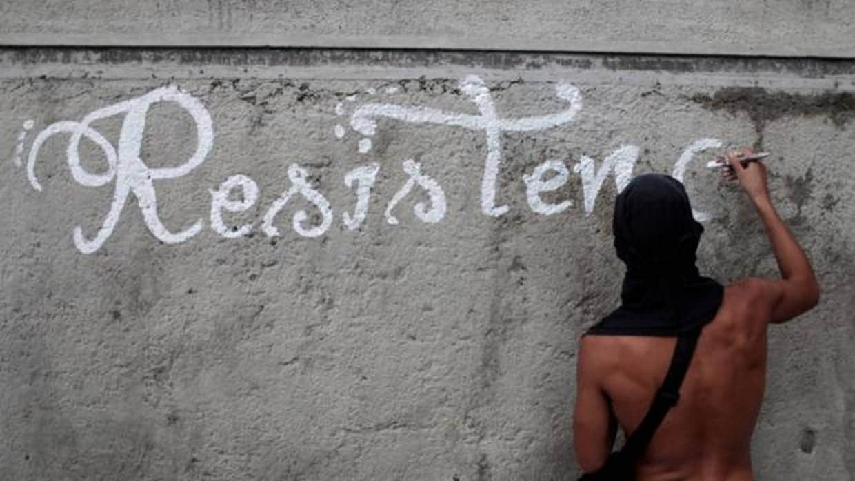 Un opositor pinta la palabra «resistencia» para denunciar el gobierno de Nicolás Maduro