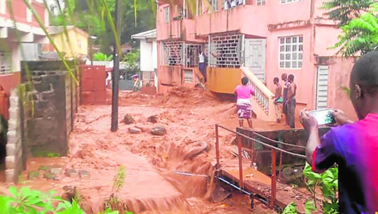 Un hombre toma una fotografía del agua anegando un barrio en Regent , cerca de Freetown