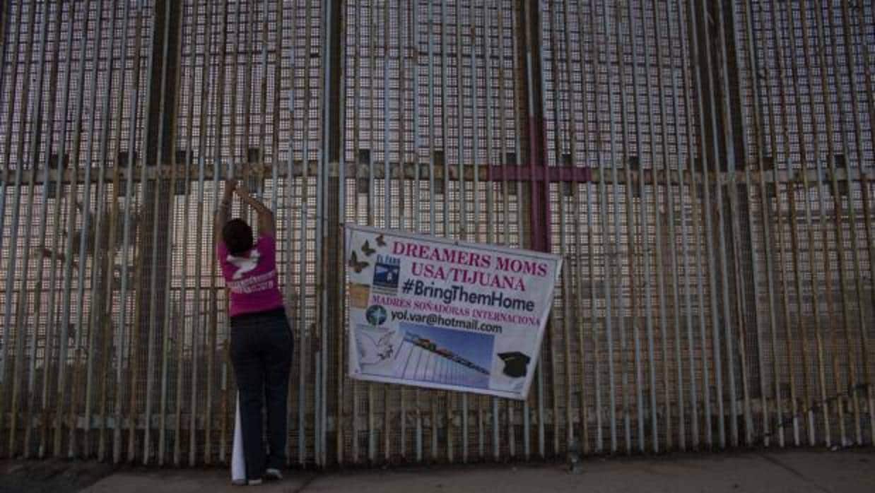 Una mujer cuelga una pancarta en la pared entre México y Estados Unidos durante una protesta contra el fin del programa DACA en Playas de Tijuana, Baja California