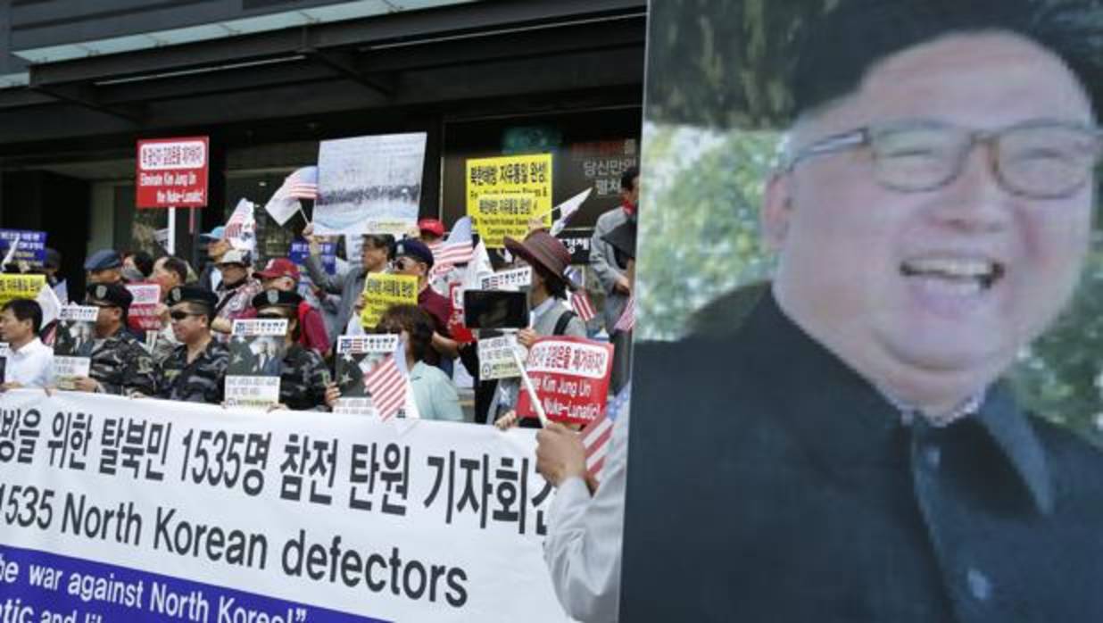 A la izq: Desertores de Corea del Norte y activistas gritan eslóganes. A la dcha: imagen de Kim Jong-un