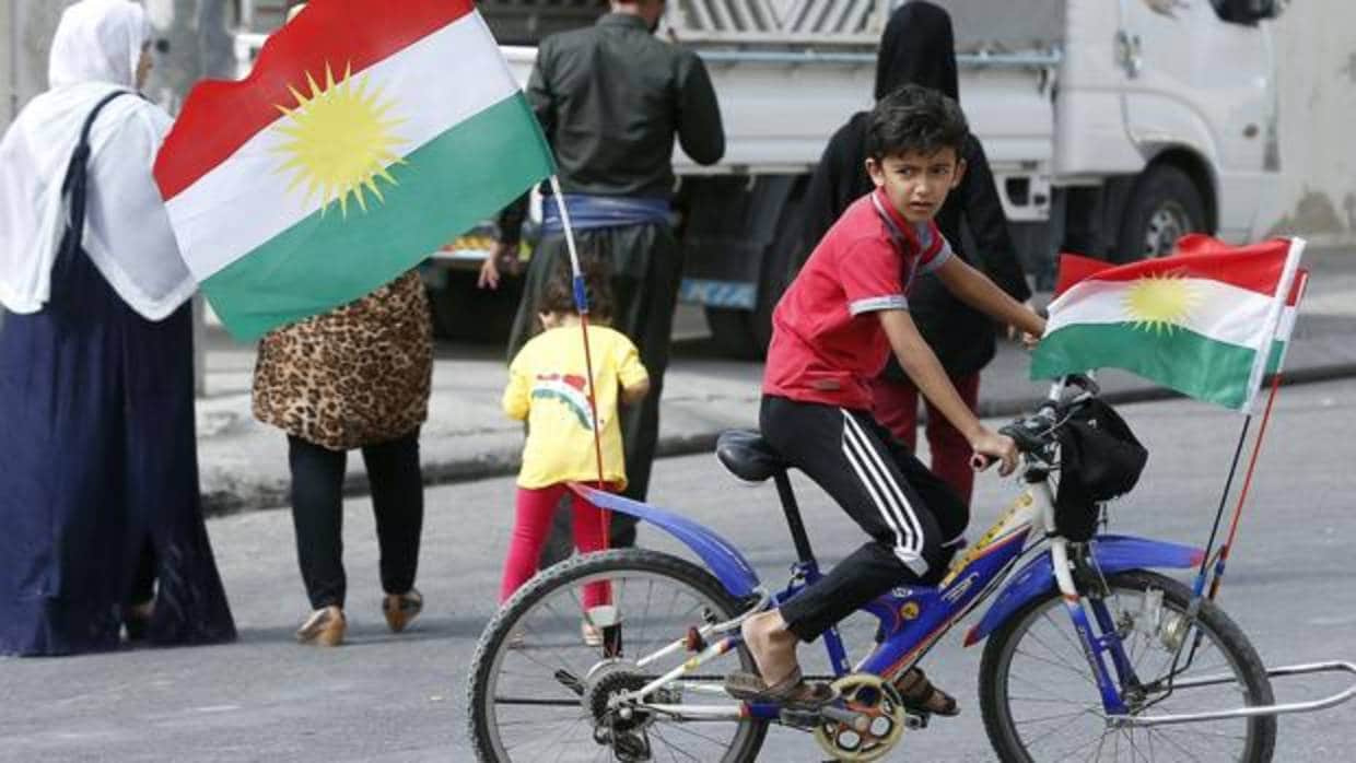 Un niño kurdo monta en una bici decorada con banderas kurdas frente a un centro electoral en Erbil, en la región autónoma del Kurdistán iraquí