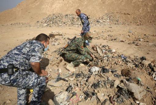 Soldados iraquíes examinan la fosa común con 500 cadáveres, pertenecietes a los presos de Badush