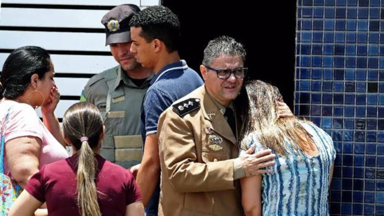 Un oficial de la Policia militar consuela a una mujer en el lugar de un tiroteo en una escuela de Brasil