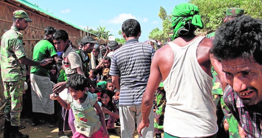 Con los ojos idos como posesos, un grupo de refugiados desesperados se abalanza sobre el reparto de comida